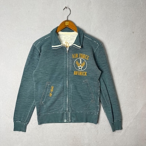 Peut inclure: Veste zipp&eacute;e bleu sarcelle avec l'inscription "AIR FORCE" et "AVIREX" en jaune. Col blanc et poche avec "LAF-1940". La veste est suspendue &agrave; un cintre m&eacute;tallique. V&ecirc;tement de style vintage.