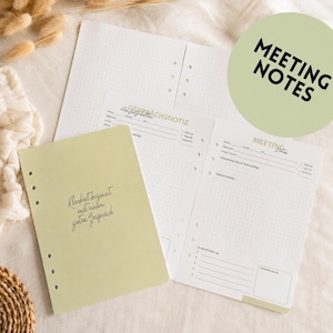 Op de afbeelding: Een set notulen en notitiepapier met een stippenrasterpatroon. De kaft van het notitieboek is lichtgroen met de tekst "Klarheit beginnt mit einem guten Gespräch". Een groene cirkel met de woorden "MEETING NOTES" staat rechtsboven.