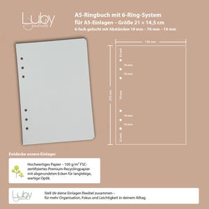 May include: A5 ring binder with a 6-ring system. The light grey binder has six holes for inserts. Dimensions are 21 cm x 14.5 cm. Text on the image includes "Entdecke unsere Einleger" and details about the paper quality.