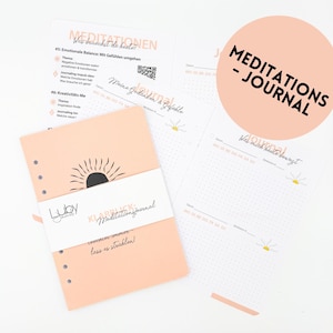 Könnte beinhalten: Ein pfirsichfarbenes Journal mit einem schwarzen Sonnendesign und den Worten "KLARBLICK Meditationsjournal" in Weiß. Das Journal wird von losen Blättern mit gepunkteten Linien und dem Text "MEDITATIONS - JOURNAL" begleitet.