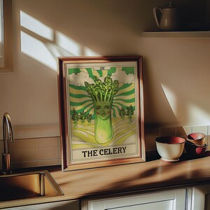 May include: A framed art print featuring a whimsical illustration of a celery stalk with a smiling face. The artwork has a vintage style with green, yellow, and cream colors. The text "THE CELERY" is at the bottom.