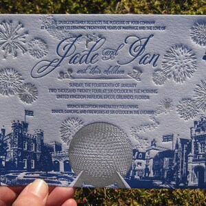 May include: A blue and white wedding invitation with a silver embossed image of the Epcot ball. The invitation text reads "The Spurgeon family requests the pleasure of your company at a ceremony celebrating twenty-five years of marriage and the love of Jade and Jan and their children. Sunday, the fourteenth of January two thousand twenty four, at six o'clock in the morning United Kingdom Pavilion, Epcot, Orlando, Florida. Brunch reception immediately following dinner, dancing, and fireworks at six o'clock in the evening."