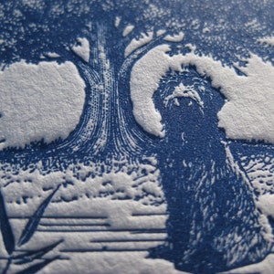 May include: A detailed blue and white illustration featuring a tree, a seated creature, and foliage. The artwork has a textured appearance, with the design elements standing out against the background. The style is reminiscent of a vintage print.