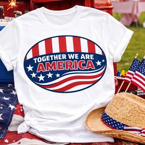 Könnte beinhalten: Weißes T-Shirt mit patriotischem Design. Das Design zeigt den Text "TOGETHER WE ARE AMERICA" in einem rot-weiß-blauen Oval. Das Shirt wird mit einem Strohhut, amerikanischen Flaggen und einer Kühlbox präsentiert.