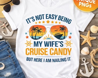 May include: White t-shirt with a colorful graphic featuring sunglasses with a beach scene and the text "IT'S NOT EASY BEING MY WIFE'S CRUISE CANDY BUT HERE I AM NAILING IT". The shirt has a nautical theme.