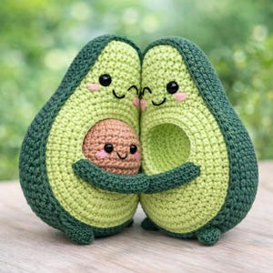 Può includere: Famiglia di avocado all'uncinetto con facce sorridenti. Due avocado verdi abbracciano un nocciolo di avocado marrone, creando una scena commovente. Gli avocado hanno occhi neri e guance rosa, perfetti per l'arredamento di una cameretta o cucina.