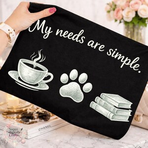 May include: Black fabric with the text "My needs are simple." features a coffee cup, a paw print, and a stack of books. The illustrations are in white, creating a contrast against the dark background.