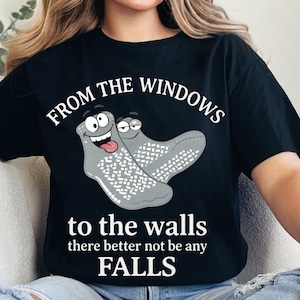 Puede incluir: Camiseta negra con el texto "FROM THE WINDOWS to the walls there better not be any FALLS". La camiseta presenta un dibujo animado de dos calcetines grises con caras.