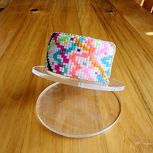 Puede incluir: Un brazalete de cuentas de colores con un patrón geométrico en tonos de rosa, azul, verde, amarillo y blanco.