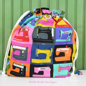 May include: A colorful drawstring bag with a pattern of vintage sewing machines. The bag is made of fabric and has a white drawstring.
