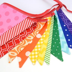 May include: A rainbow-coloured fabric banner with a variety of patterns, including polka dots, stripes, and geometric designs. The banner is made of cotton fabric and is perfect for decorating a party or adding a touch of colour to a room.
