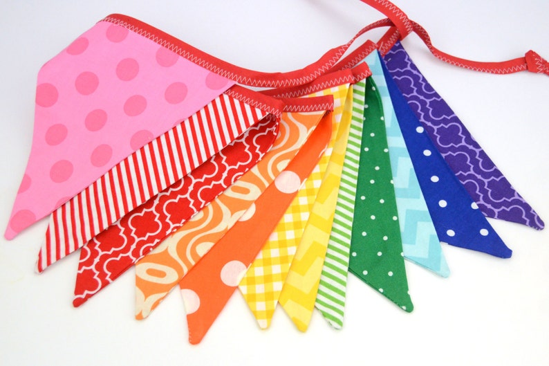 May include: A rainbow-coloured fabric banner with a variety of patterns, including polka dots, stripes, and geometric designs. The banner is made of cotton fabric and is perfect for decorating a party or adding a touch of colour to a room.