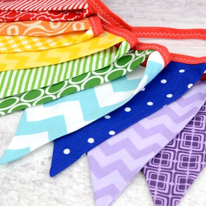 May include: A rainbow fabric banner with different patterns on each flag. The flags are red, orange, yellow, green, blue, and purple.