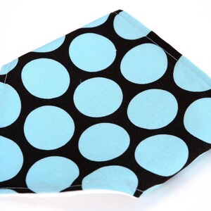 May include: A black and blue polka dot fabric bib with white edging.
