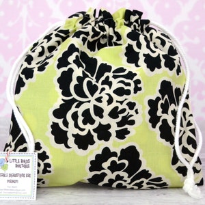 May include: A lime green drawstring bag with a black and white floral pattern. The bag has white drawstrings and a tag that reads "Little Birds Boutique Reusable Drawstring Bag Medium".