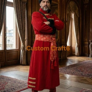 May include: A long, vibrant red coat featuring a wide, patterned orange sash tied at the waist with decorative tassels. The coat includes gold-toned horizontal trim details on the lower front panels and a black fur-like accent on the shoulder.