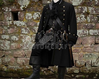 May include: A black pirate-style coat with gold buttons, paired with matching pants and boots. The outfit includes a black vest, a ruffled neckpiece, and a sword. The mannequin stands on a stone, against a brick wall.
