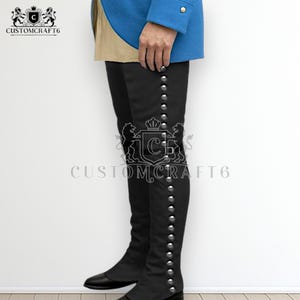 May include: Black knee-high boots with silver-colored button details. The boots are part of a historical costume, with the Customcraft6 logo visible. The boots are worn with a blue jacket.