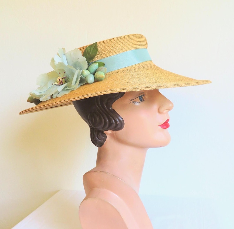 Peut inclure: Un chapeau de paille &agrave; larges bords avec un ruban bleu clair et une fleur en guise d'ornement. Le chapeau est port&eacute; sur la t&ecirc;te d'un mannequin.