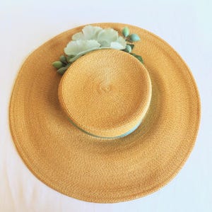 Peut inclure: Un chapeau de paille &agrave; large bord avec un ruban bleu clair et une fleur bleue clair.