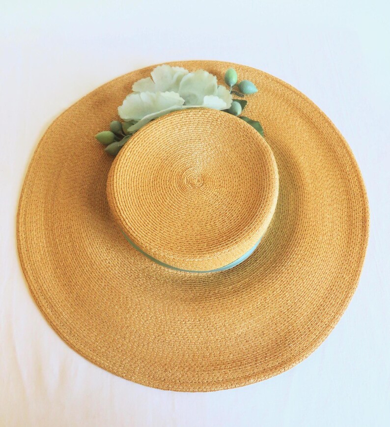 Peut inclure: Un chapeau de paille &agrave; large bord avec un ruban bleu clair et une fleur bleue clair.