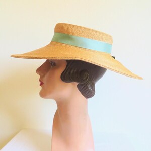 Peut inclure: Un chapeau de paille &agrave; larges bords avec un ruban bleu clair. Le chapeau est sur une t&ecirc;te de mannequin.