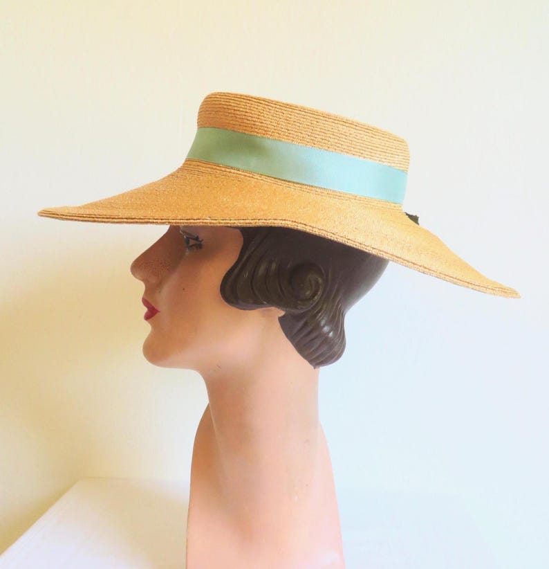 Peut inclure: Un chapeau de paille &agrave; larges bords avec un ruban bleu clair. Le chapeau est sur une t&ecirc;te de mannequin.