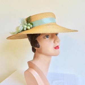 Peut inclure: Un chapeau de paille &agrave; larges bords avec un ruban bleu clair et une fleur.