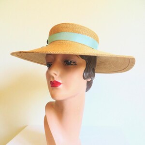 Peut inclure: Un chapeau de paille &agrave; larges bords avec un ruban bleu clair autour de la couronne. Le chapeau est port&eacute; sur la t&ecirc;te d'un mannequin.