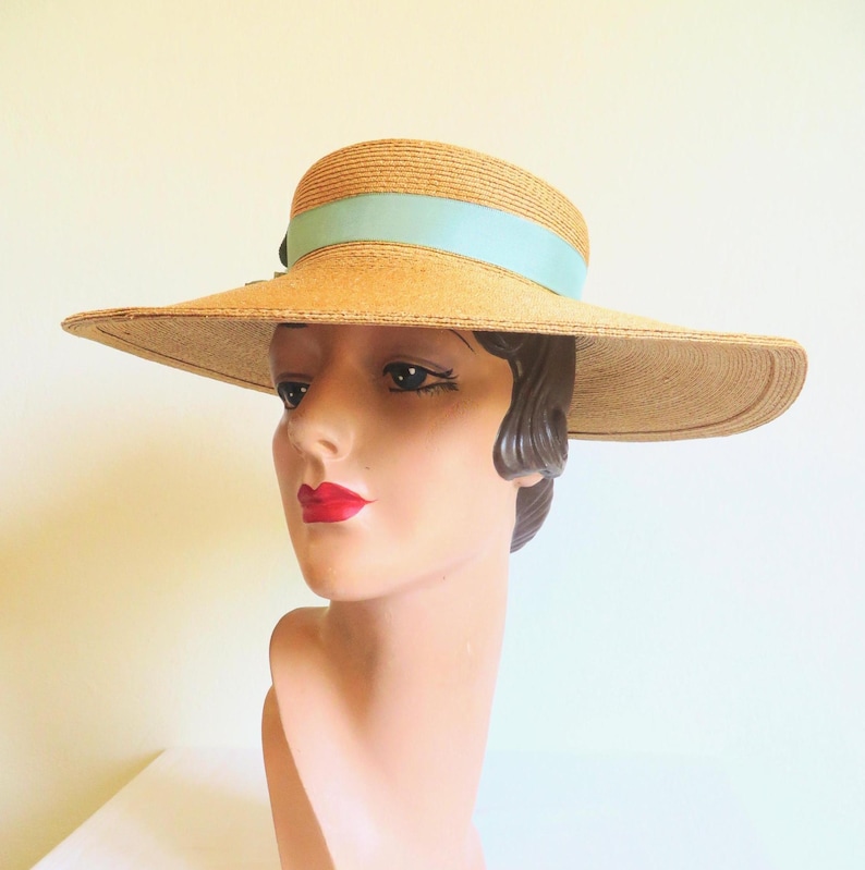 Peut inclure: Un chapeau de paille &agrave; larges bords avec un ruban bleu clair autour de la couronne. Le chapeau est port&eacute; sur la t&ecirc;te d'un mannequin.
