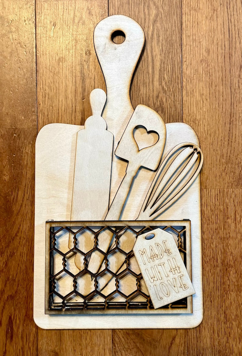 Puede incluir: Conjunto de decoraci&oacute;n de cocina de madera con una tabla de cortar, un rodillo, una esp&aacute;tula, un batidor y una cesta de alambre con una etiqueta que dice "Made with Love".