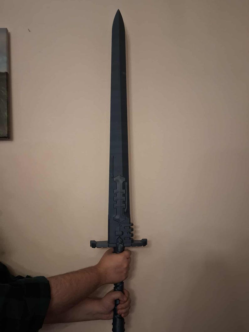 May include: A large, dark grey sword with a long, pointed blade. The hilt features intricate geometric designs and a crossguard. The sword is held by a person. The design suggests a fantasy or historical theme.