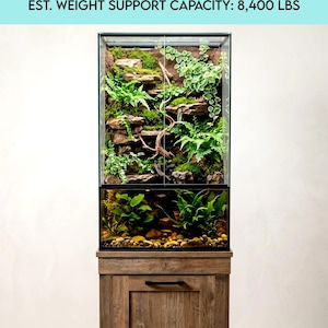 May include: A 10-gallon solid wood paludarium stand with a glass enclosure filled with plants and a water feature. The stand is made of wood and has a cabinet door. The text on the image reads "BUILDING INSTRUCTIONS" and "EST. WEIGHT SUPPORT CAPACITY: 8,400 LBS."