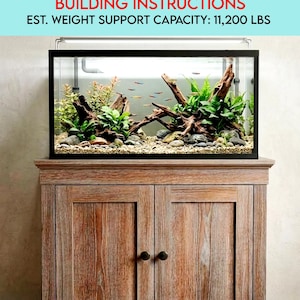 May include: A 50-gallon aquarium on a solid wood stand. The tank features aquatic plants, driftwood, and small fish. The stand has two doors with dark knobs and is made of light-coloured wood. The image text reads: "BUILDING INSTRUCTIONS" and "EST. WEIGHT SUPPORT CAPACITY: 5080 kg."