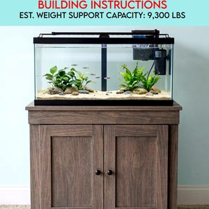 May include: A wooden aquarium stand with a 113-litre tank. The stand has two cabinet doors with black knobs. The tank contains plants, rocks, and fish. The text on the image reads: "30 GALLON SOLID WOOD AQUARIUM STAND BUILDING INSTRUCTIONS EST. WEIGHT SUPPORT CAPACITY: 9,300 LBS."