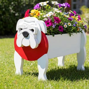 K&ouml;nnte beinhalten: Ein wei&szlig;er Holz-Bulldoggen-Pflanzk&uuml;bel mit rotem Kragen, gef&uuml;llt mit bunten Blumen. Der Pflanzk&uuml;bel ist wie eine Bulldogge geformt, mit Kopf und Beinen sichtbar. Die Blumen umfassen lila, wei&szlig;e, gelbe und rosa Bl&uuml;ten und bilden eine lebendige Darstellung.