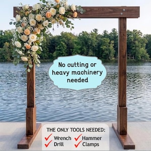 May include: A freestanding wooden arch frame with a dark brown finish, decorated with a floral arrangement of white and peach roses and eucalyptus. Text overlays include: Solid, Sturdy, Portable, Freestanding, No cutting or heavy machinery needed, THE ONLY TOOLS NEEDED: Wrench, Drill, Hammer, Clamps, and All materials are linked! Costs under $50 to build.