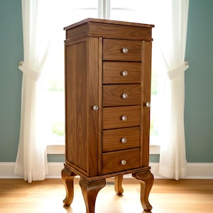 May include: A tall, wooden jewelry armoire with a rich, brown finish. It features six drawers with crystal knobs, two side doors, and ornate, curved legs. The armoire stands in front of a window with white curtains.
