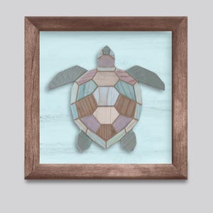 Op de afbeelding: Ingelijst kunstwerk met een mozaïek schildpad ontwerp. De schildpad is gemaakt van pastelkleurige houten stukken in blauw, groen, roze en bruin. De achtergrond is lichtblauw en de lijst is donkerbruin. Geschikt voor een kustthema.