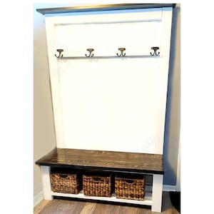 May include: A wooden entryway bench with a dark stained top and white base. It features three woven baskets for storage and a row of four bronze-colored hooks. The bench is designed for organization and storage.
