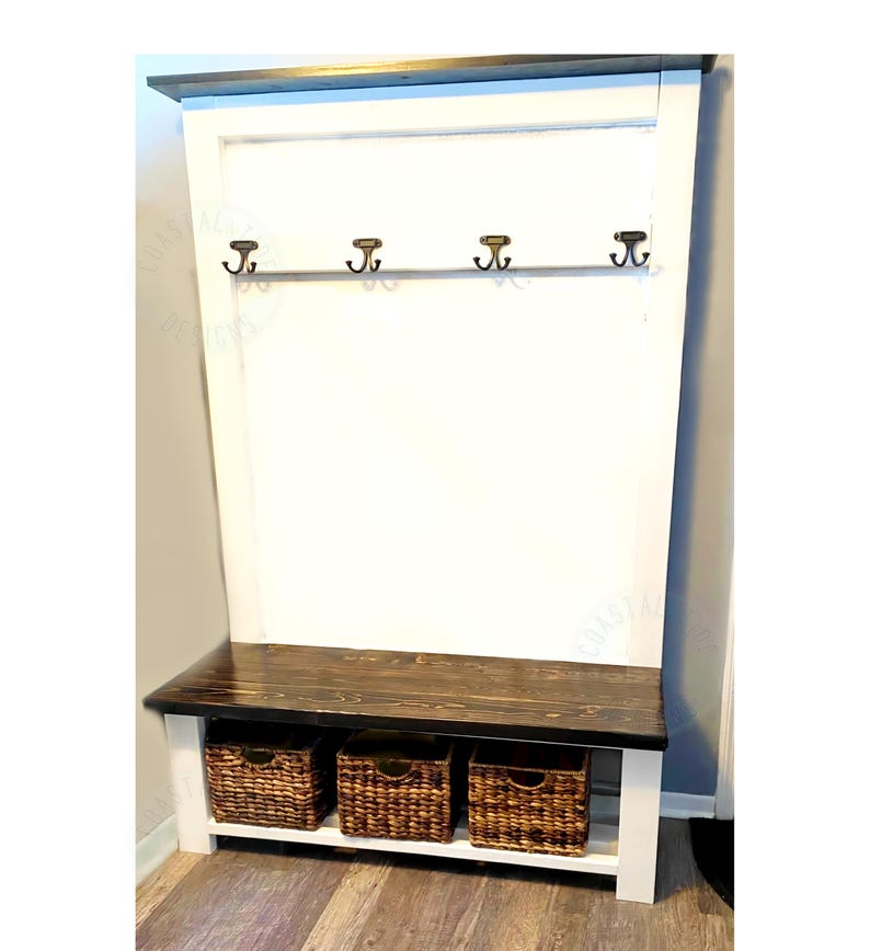 May include: A wooden entryway bench with a dark stained top and white base. It features three woven baskets for storage and a row of four bronze-colored hooks. The bench is designed for organization and storage.