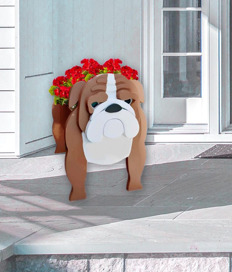 K&ouml;nnte beinhalten: Ein Holz-Blumentopf in Form einer Bulldogge, braun und wei&szlig;, gef&uuml;llt mit roten Blumen. Die Bulldogge hat einen traurigen Gesichtsausdruck und steht in der N&auml;he einer wei&szlig;en T&uuml;r.