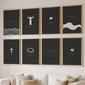 May include: Eight framed art prints with black backgrounds and minimalist white illustrations. The prints feature religious symbols and quotes, displayed above a white sofa with beige cushions. The frames are a light wood colour.