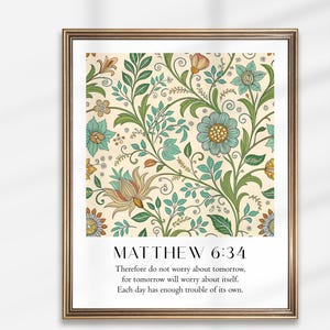 Könnte beinhalten: Gerahmter Kunstdruck mit floralem Muster in Grün, Blau und Orange auf cremefarbenem Hintergrund. Der Druck enthält den Text "MATTHÄUS 6:34" und ein Zitat. Der Rahmen ist goldfarben.