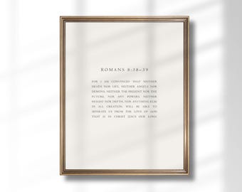 May include: A framed print with the text "ROMANS 8:38-39" in a serif font. The text is centered on a cream-colored background, within a gold-colored frame. The text is a passage from the Bible.