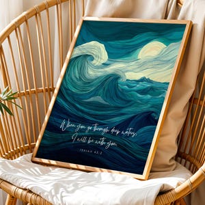 May include: A framed art print featuring an abstract ocean wave design in shades of blue and white. The artwork includes the text "When you go through deep waters, I will be with you. Isaiah 43:2." The print is displayed on a wicker chair.