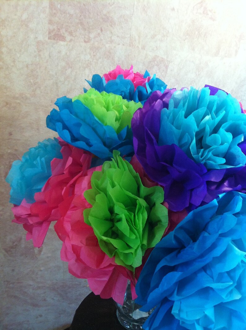 Puede incluir: Un ramo de flores de papel de seda en una variedad de colores, incluyendo rosa, azul, verde y morado. Las flores est&aacute;n dispuestas en un jarr&oacute;n y son una decoraci&oacute;n festiva.
