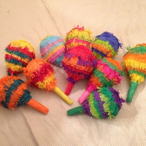 May include: A group of colorful pinatas made of tissue paper. The pinatas are shaped like cones and have a variety of colors, including red, yellow, green, blue, and purple.