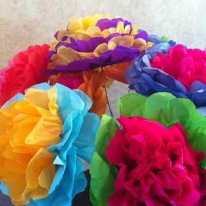 Puede incluir: Un ramo de flores de papel de seda de colores en tonos de azul, amarillo, naranja, rosa y verde. Las flores est&aacute;n dispuestas en forma circular y est&aacute;n hechas para parecer claveles.