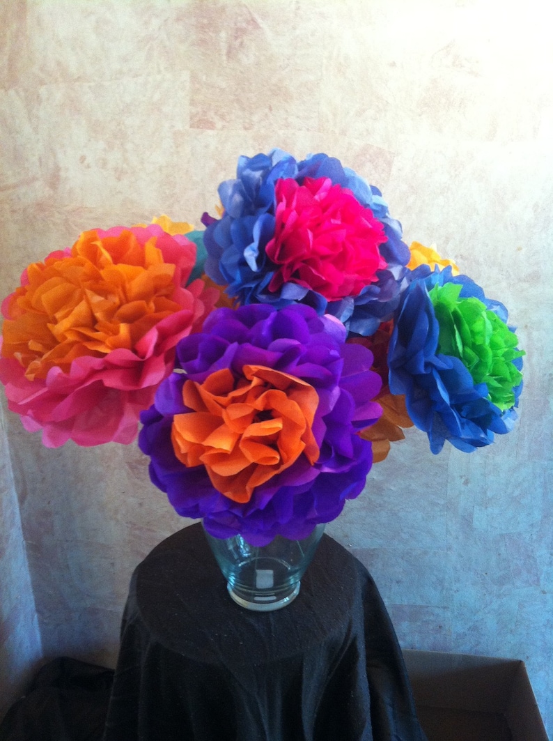 Puede incluir: Un ramo de flores de papel de seda de colores en un jarr&oacute;n de vidrio transparente. Las flores son en tonos de naranja, rosa, morado, azul y verde.